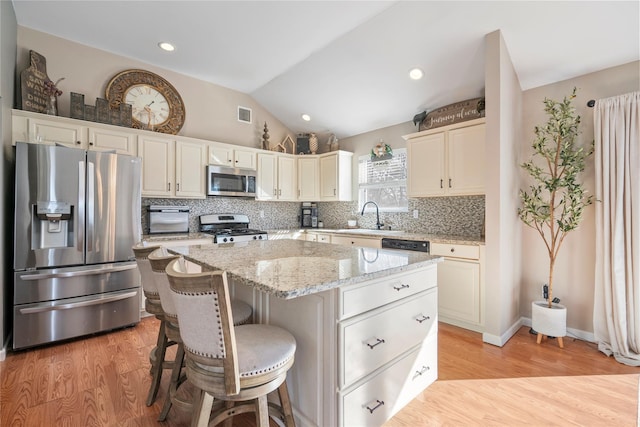 kitchen with stainless steel appliances, vaulted ceiling, a sink, and decorative backsplash