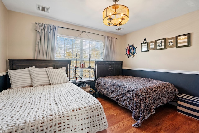 bedroom featuring a chandelier, visible vents, and wood finished floors