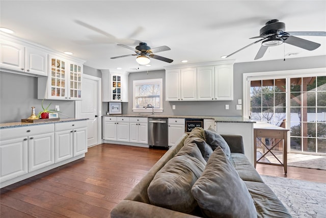 kitchen with recessed lighting, white cabinets, stainless steel dishwasher, dark wood finished floors, and glass insert cabinets