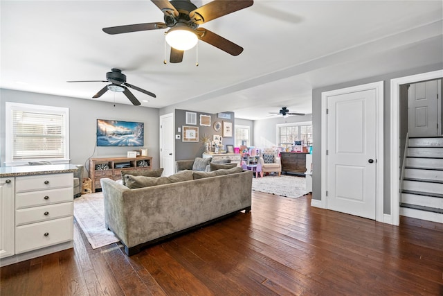 living area with dark wood-style flooring, stairway, and baseboards