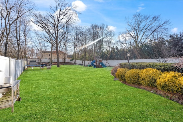 view of yard featuring a trampoline, playground community, and a fenced backyard