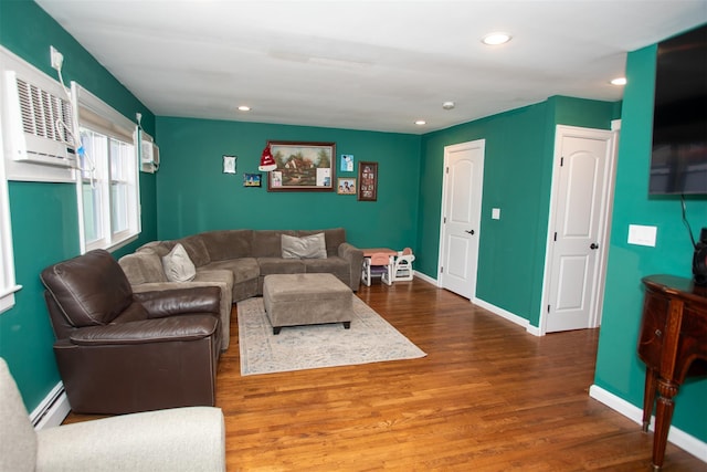 living area with a baseboard radiator, recessed lighting, a wall mounted AC, wood finished floors, and baseboards