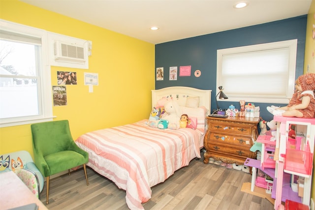 bedroom with an AC wall unit, wood finished floors, and recessed lighting