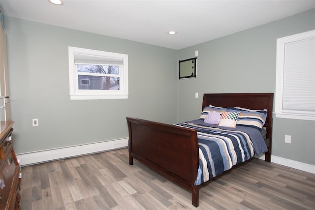 bedroom featuring baseboards, baseboard heating, wood finished floors, and recessed lighting