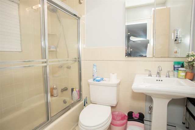 full bathroom with bath / shower combo with glass door, toilet, and tile walls