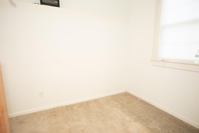 unfurnished room featuring light carpet and baseboards