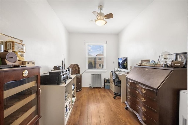 office area with a ceiling fan, radiator heating unit, and wood finished floors