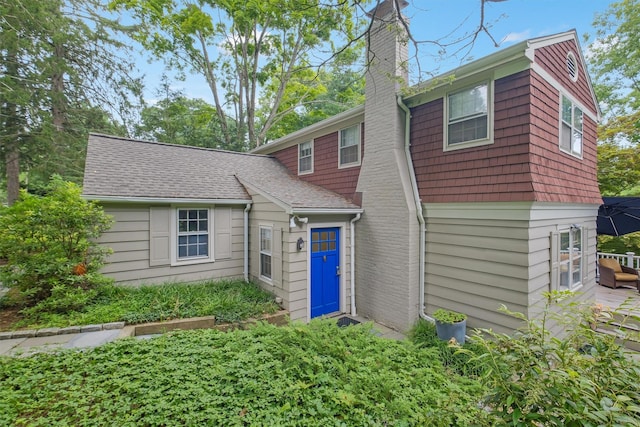 view of front of home with a shingled roof and a chimney