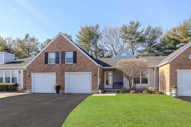 traditional-style house with aphalt driveway, a front lawn, an attached garage, and brick siding