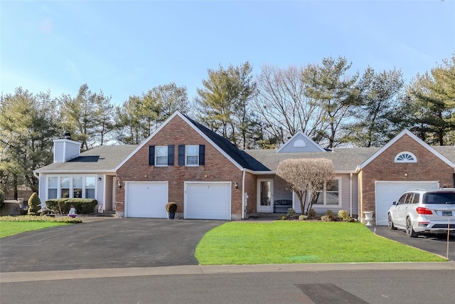 traditional-style home featuring driveway, brick siding, a chimney, and a front yard