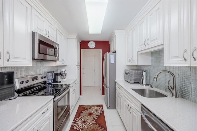 kitchen with light tile patterned floors, stainless steel appliances, backsplash, white cabinets, and a sink