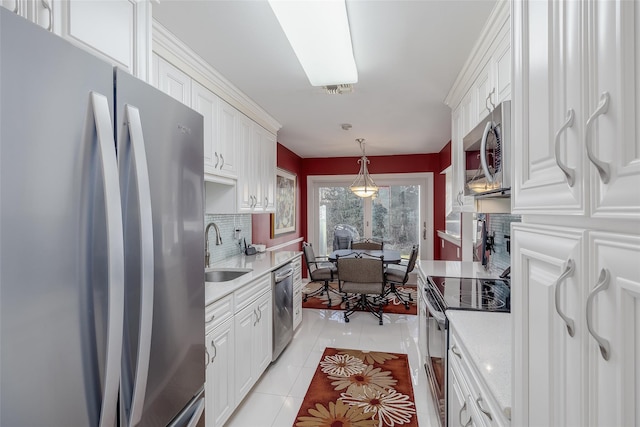 kitchen featuring white cabinets, decorative light fixtures, stainless steel appliances, light countertops, and a sink