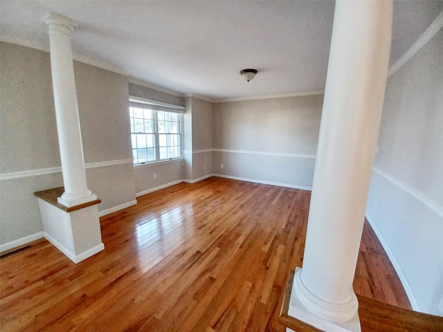 interior space featuring crown molding, ornate columns, and wood finished floors