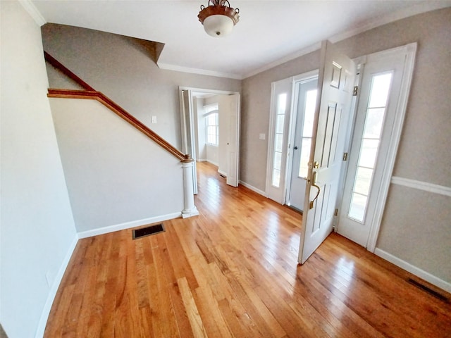 foyer with visible vents, ornamental molding, light wood-type flooring, baseboards, and stairs