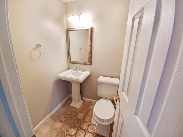 half bath featuring toilet and baseboards