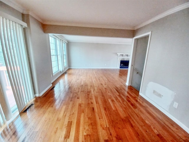 unfurnished living room with ornamental molding, light wood-type flooring, visible vents, and a fireplace