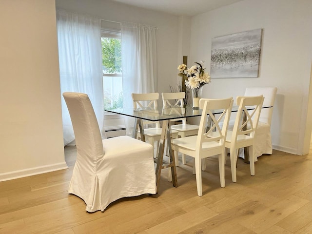 dining area with a baseboard radiator, baseboards, and wood finished floors