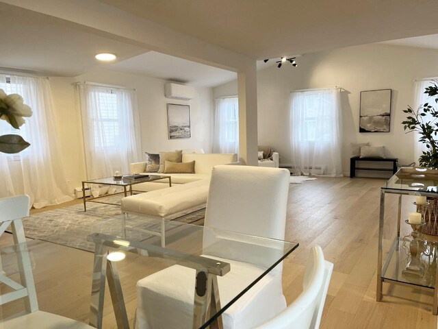 dining area with a wall unit AC, light wood-style floors, and a baseboard heating unit