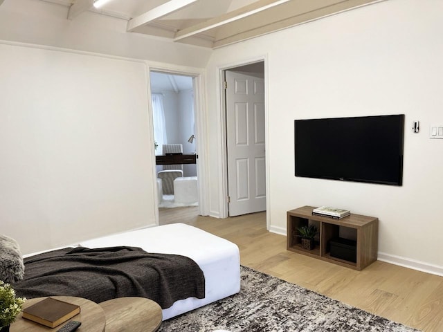 bedroom featuring beamed ceiling, light wood-type flooring, and baseboards