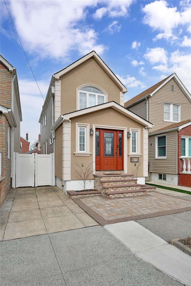 view of front of home featuring stucco siding, fence, and a gate