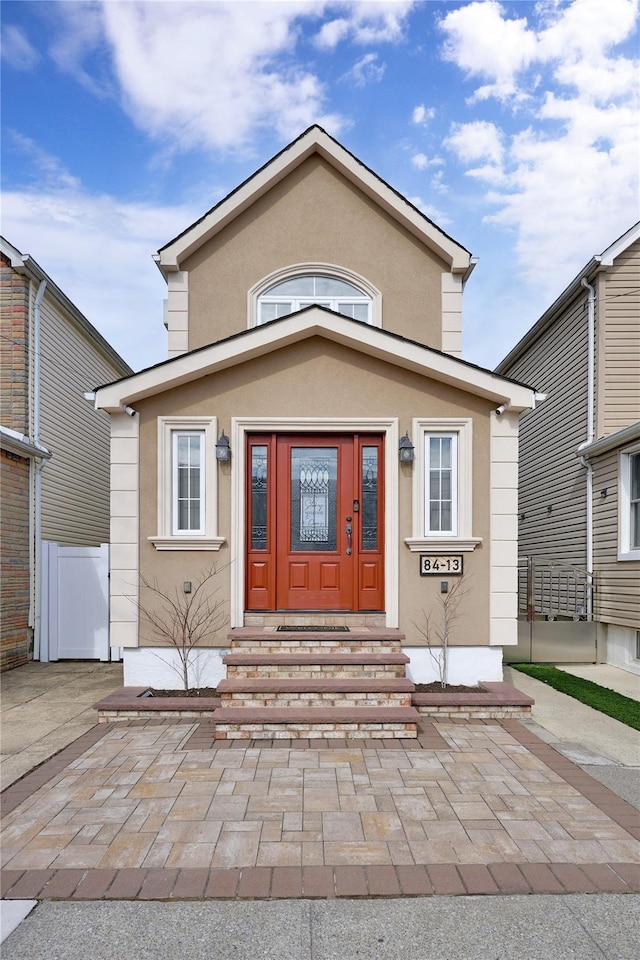 view of front of home with stucco siding, fence, and entry steps