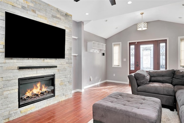 living area with a fireplace, lofted ceiling, recessed lighting, wood finished floors, and baseboards