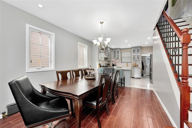 dining room featuring baseboards, stairway, wood tiled floor, a chandelier, and recessed lighting