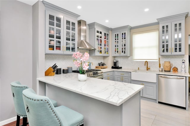 kitchen featuring stainless steel appliances, glass insert cabinets, and wall chimney exhaust hood