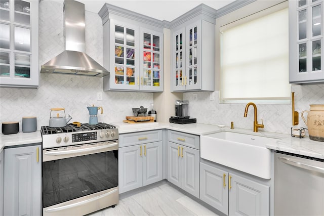 kitchen featuring glass insert cabinets, dishwasher, wall chimney range hood, and stainless steel gas range oven