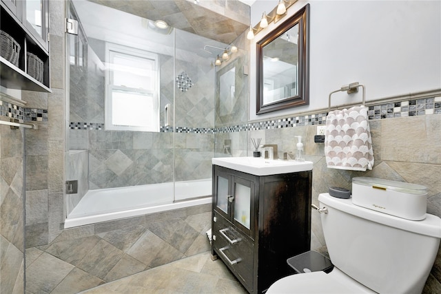 bathroom with toilet, tiled shower / bath, tile walls, and vanity