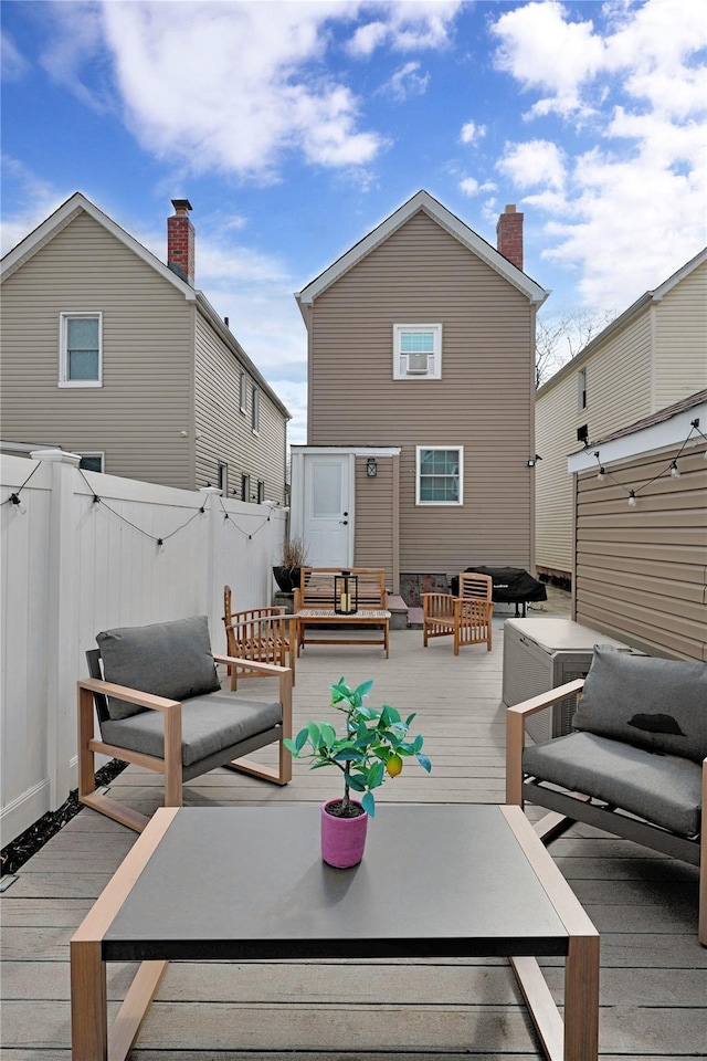 back of property with fence, a deck, and an outdoor living space