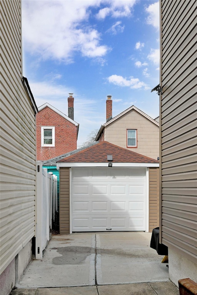 detached garage featuring concrete driveway and fence