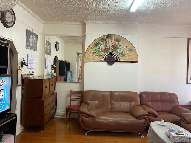 living area featuring an ornate ceiling, crown molding, and wood finished floors