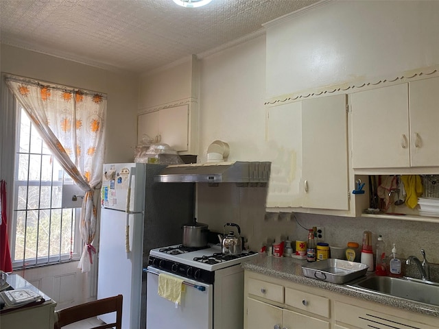 kitchen featuring white appliances, a sink, crown molding, a textured ceiling, and backsplash