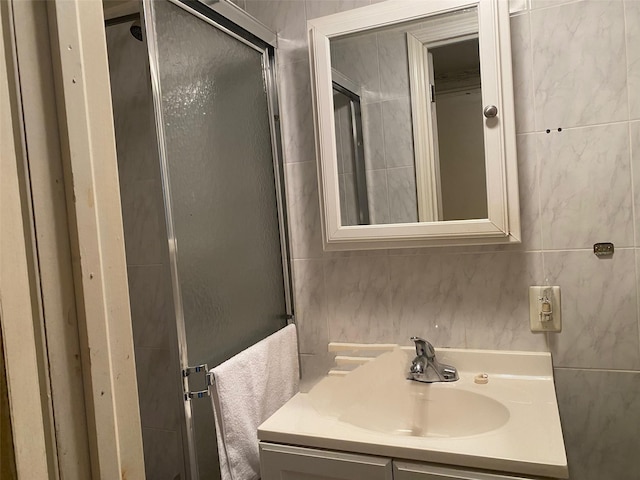 bathroom with vanity, a shower stall, and tile walls