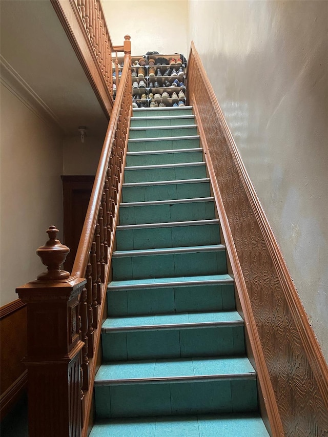 stairway featuring a wainscoted wall and crown molding