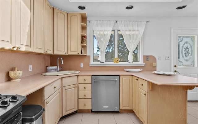 kitchen with a peninsula, light brown cabinetry, and a sink