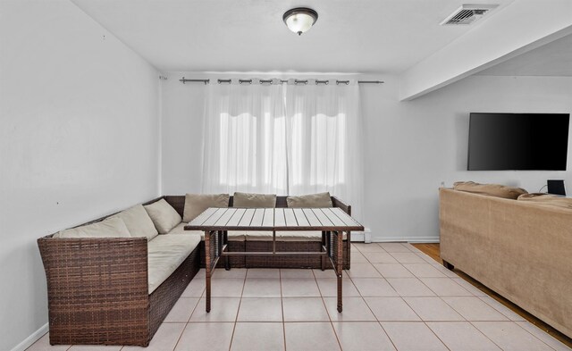 living area featuring light tile patterned floors, visible vents, breakfast area, and baseboards