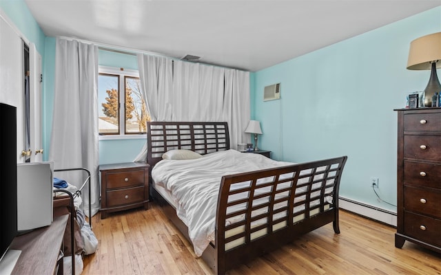 bedroom with wood-type flooring, visible vents, baseboard heating, and an AC wall unit