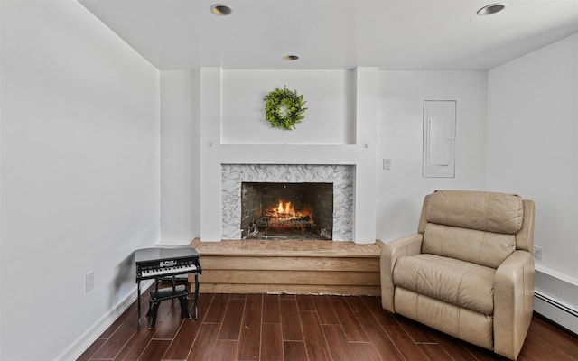 living area featuring recessed lighting, a baseboard heating unit, a high end fireplace, electric panel, and dark wood finished floors