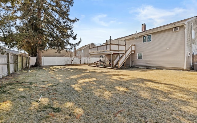 rear view of house featuring a deck, a fenced backyard, stairs, a yard, and a chimney