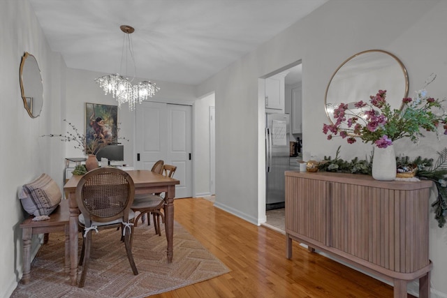 dining area featuring light wood-style floors, a chandelier, and baseboards