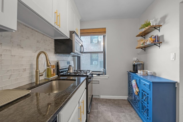 kitchen with appliances with stainless steel finishes, white cabinets, a sink, and blue cabinetry