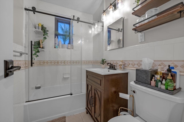 full bathroom featuring tile walls, bath / shower combo with glass door, toilet, vanity, and tile patterned floors