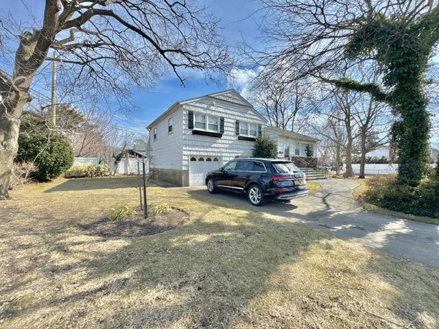 view of property exterior with driveway, a lawn, and an attached garage