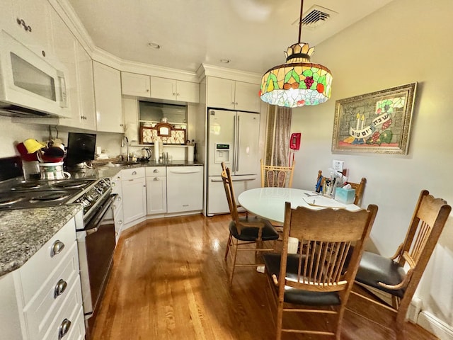 513 Dee Ct, East Meadow, NY 11554 - kitchen featuring white appliances, wood finished floors, white cabinets, and hanging light fixtures