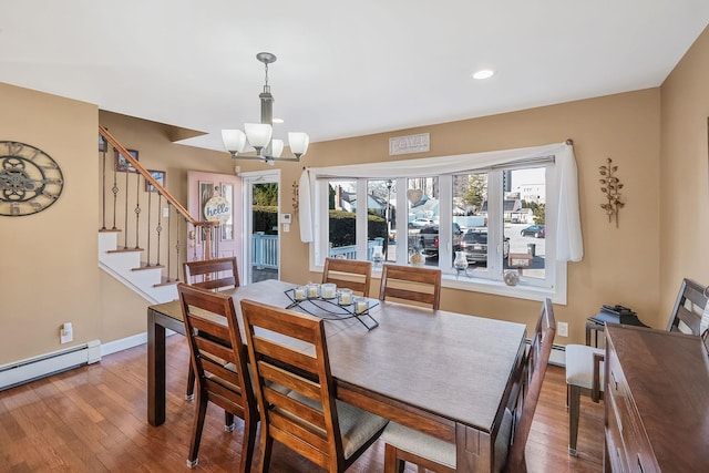 dining room with hardwood / wood-style flooring, a notable chandelier, a baseboard heating unit, baseboards, and stairs