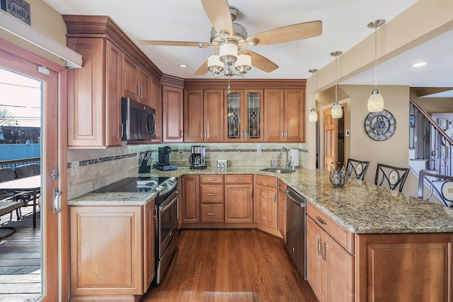 kitchen featuring a breakfast bar, a sink, hanging light fixtures, appliances with stainless steel finishes, and glass insert cabinets