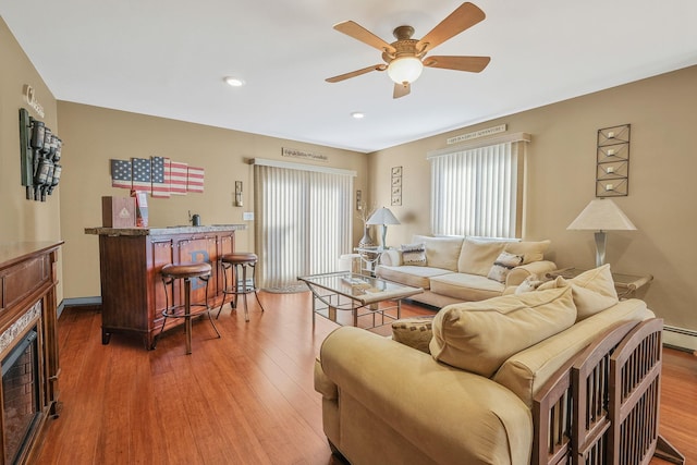 living area featuring a fireplace, a ceiling fan, and wood finished floors