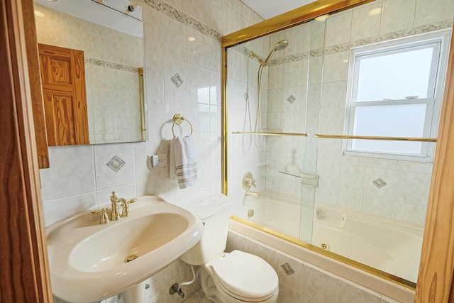 full bathroom with tile walls, decorative backsplash, toilet, tiled shower / bath, and a sink